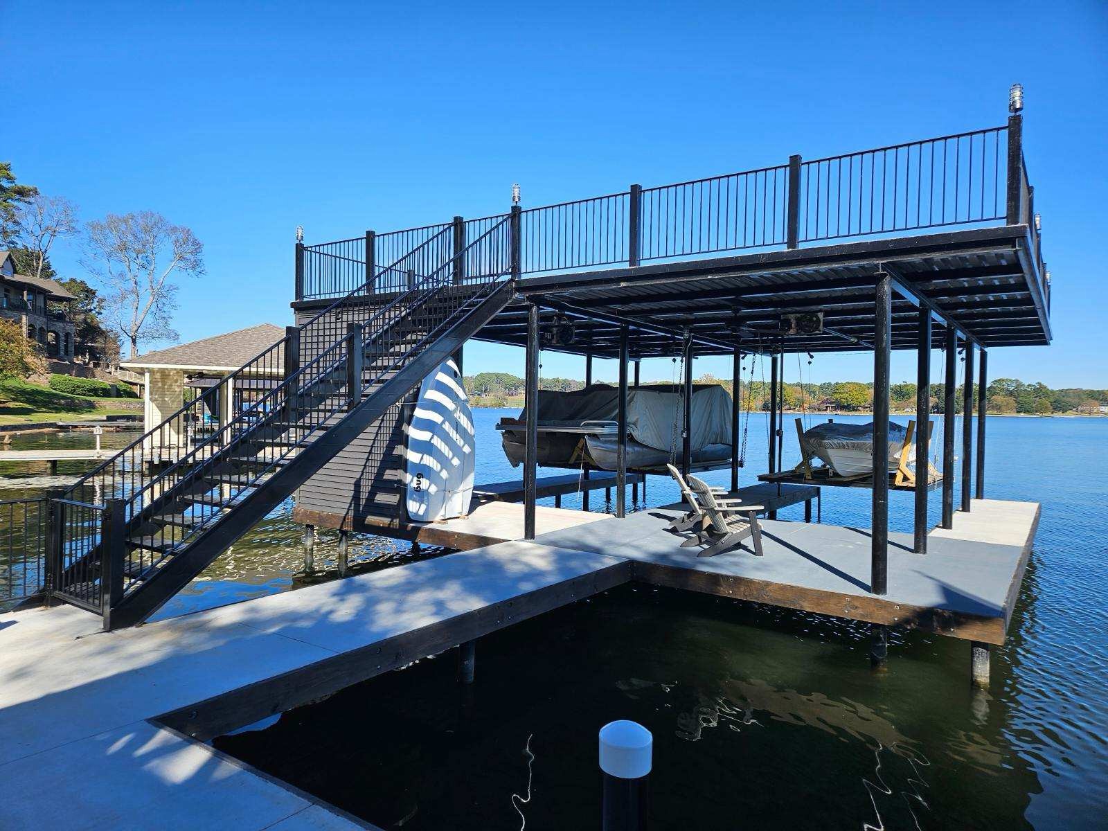 Two-story steel boat dock with rooftop sundeck and stairs on a lake